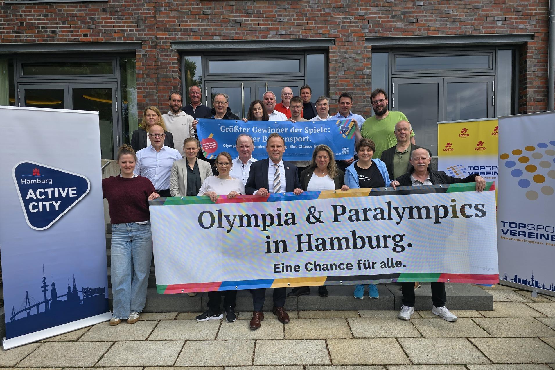 Gruppenfoto von Teilnehmern einer Veranstaltung mit Banner &bdquo;Olympia & Paralympics in Hamburg&ldquo; vor einem Geb&auml;ude.